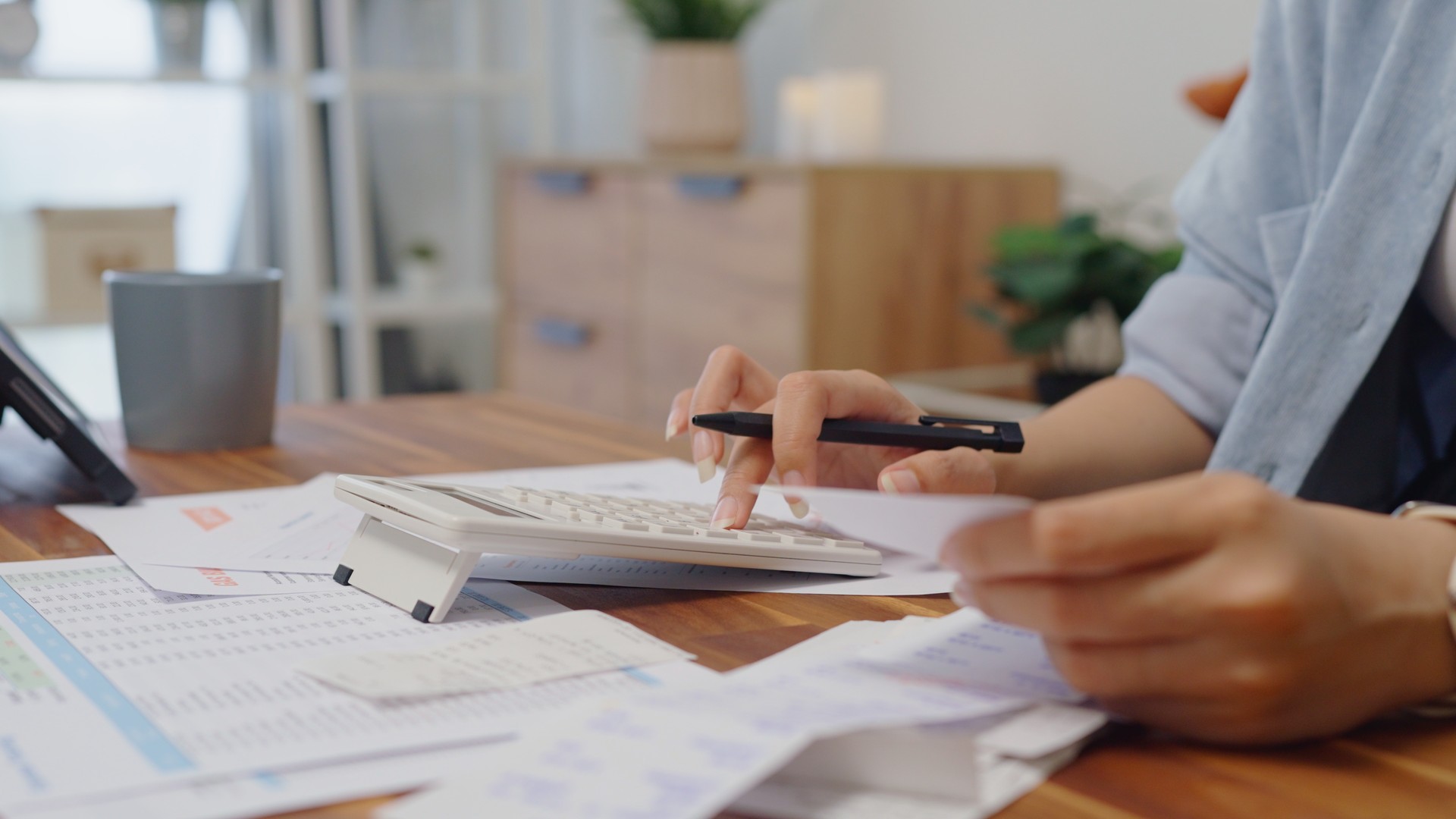 close up  woman hands calculates on calculator for personal finance, paysckeck paper receipt expense biil statement,planning budgets of monthly personal balance at home.